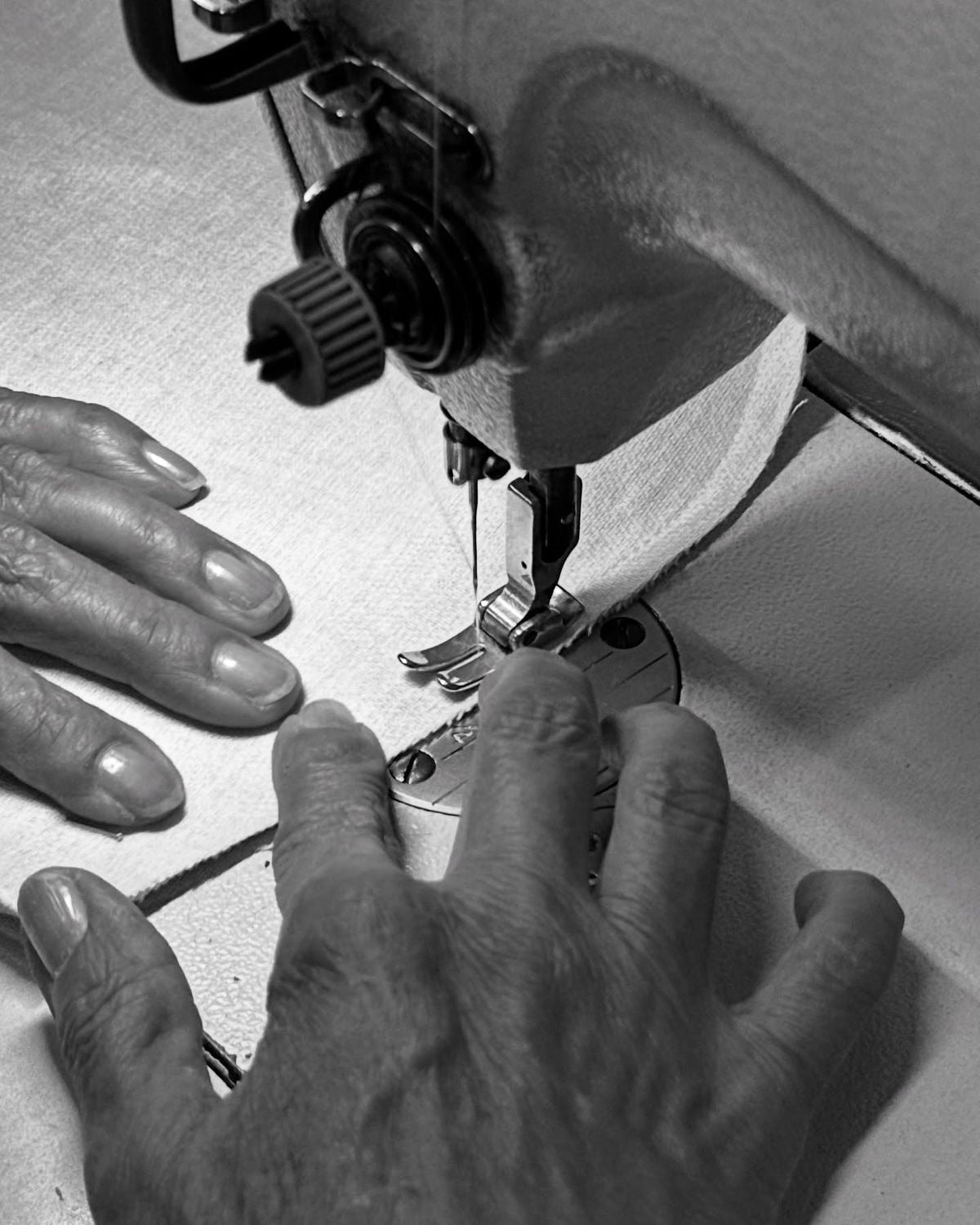 Hands guiding fabric through a sewing machine