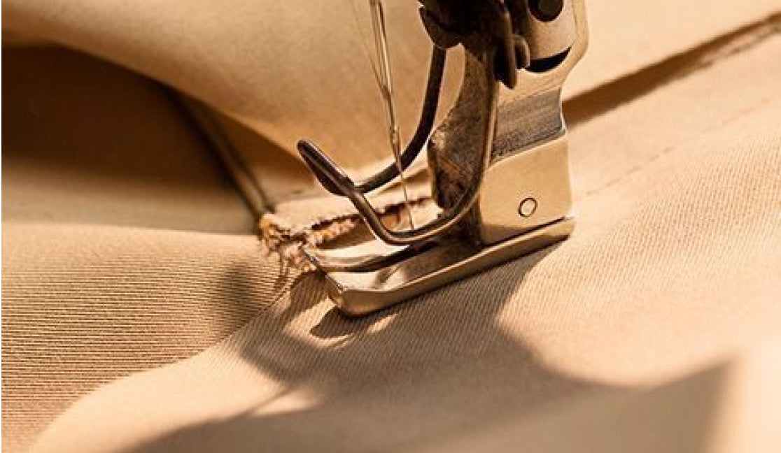 Close-up of a sewing machine stitching neutral fabric